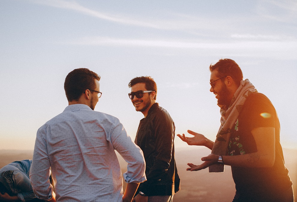 three male adults having fun at the beach with back-lit sunset