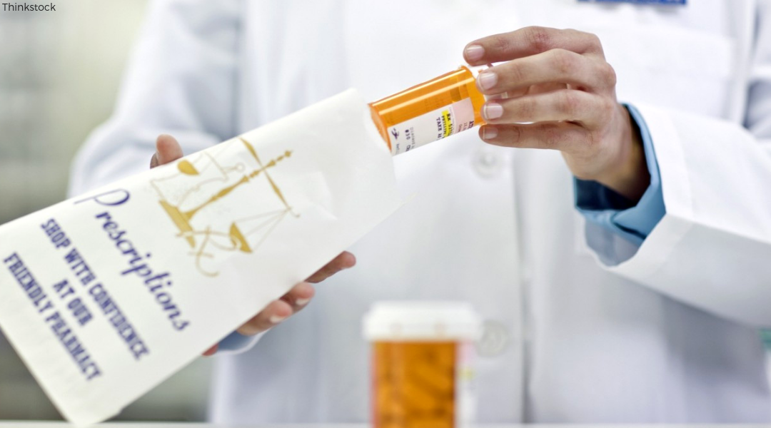 clinical pharmacist putting pill bottle inside prescription bag