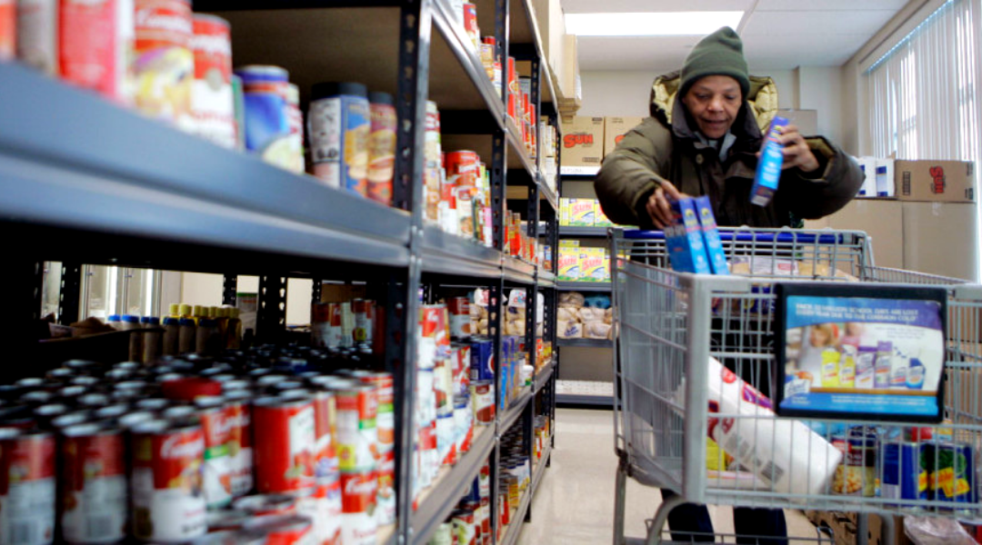 Black woman pushing a cart with food items in a grocery store