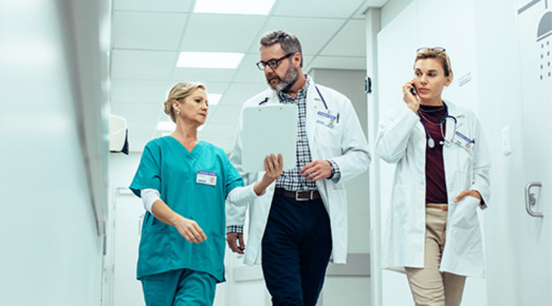 Physician, nurse, and technician walk through clinic hallway