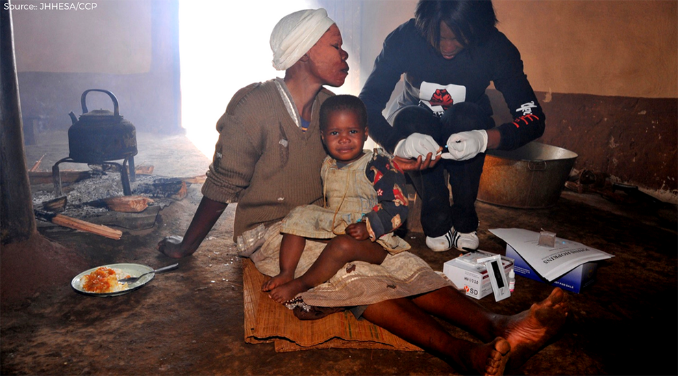 African mother with her infant child being tested for HIV by healthcare outreach worker