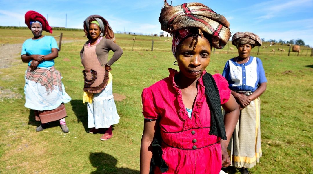 Four South African women standing in a grassy field.