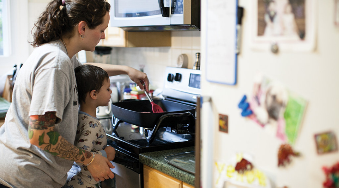 A woman helps a child cooking