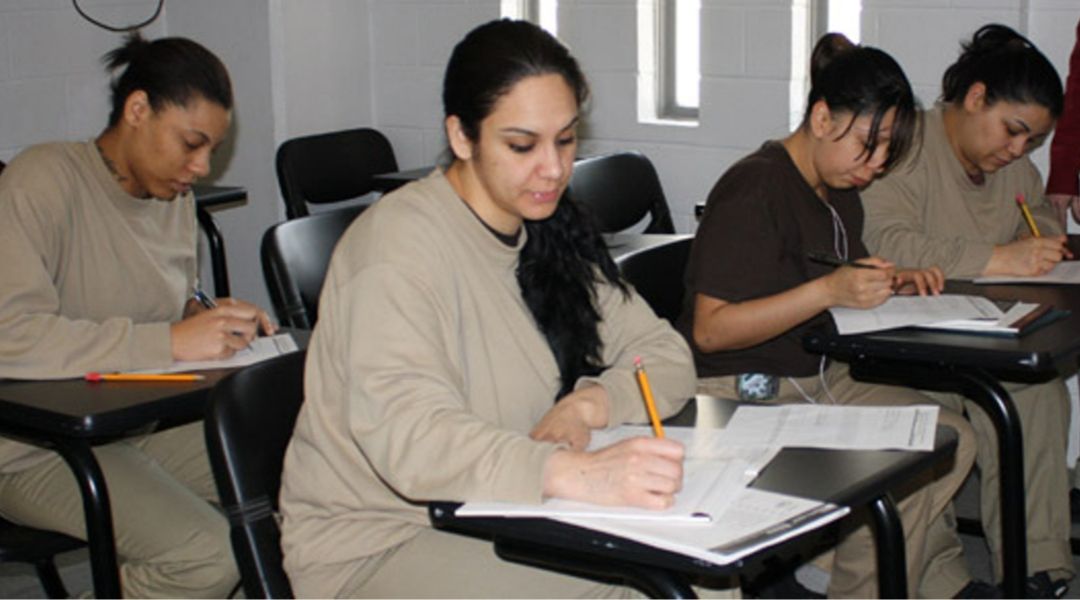 Four incarcerated women attending a class, sitting in desks