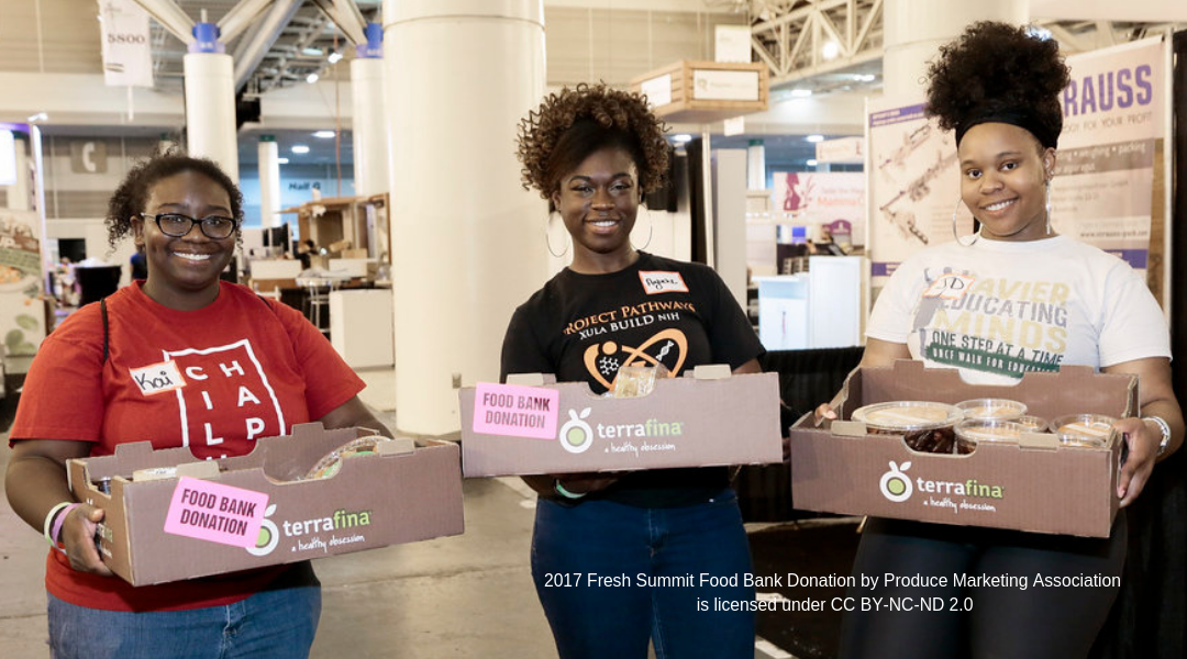 Three African American women volunteering at a food bank holding boxes