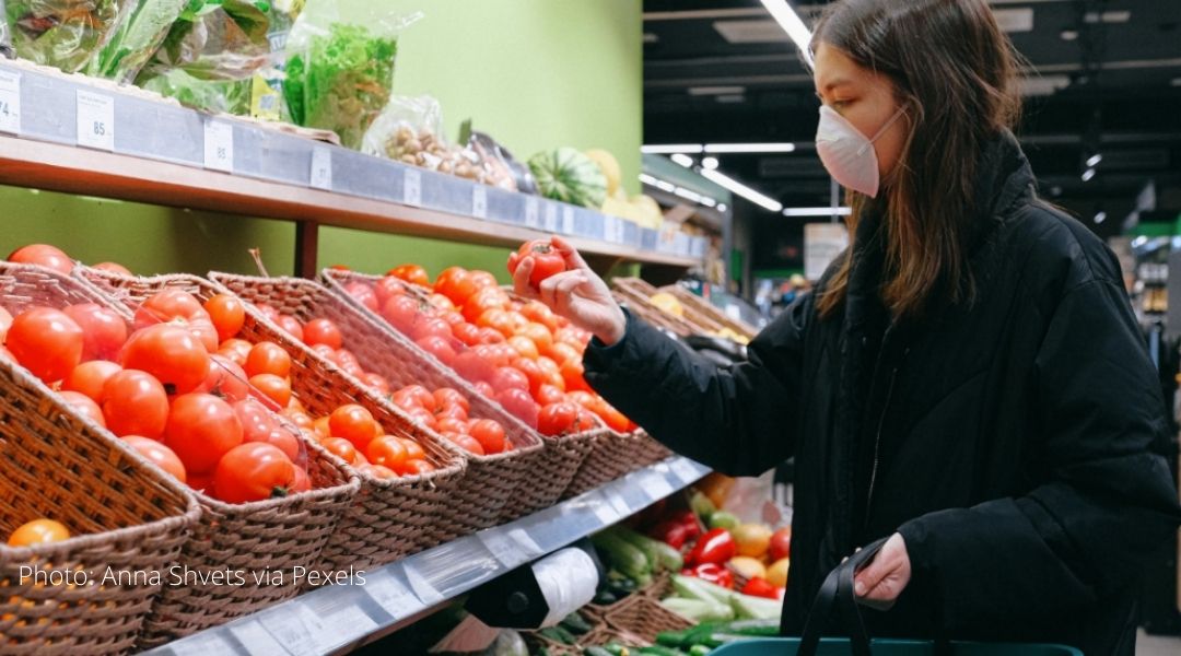 A woman shops for produce wearing a COVID mask