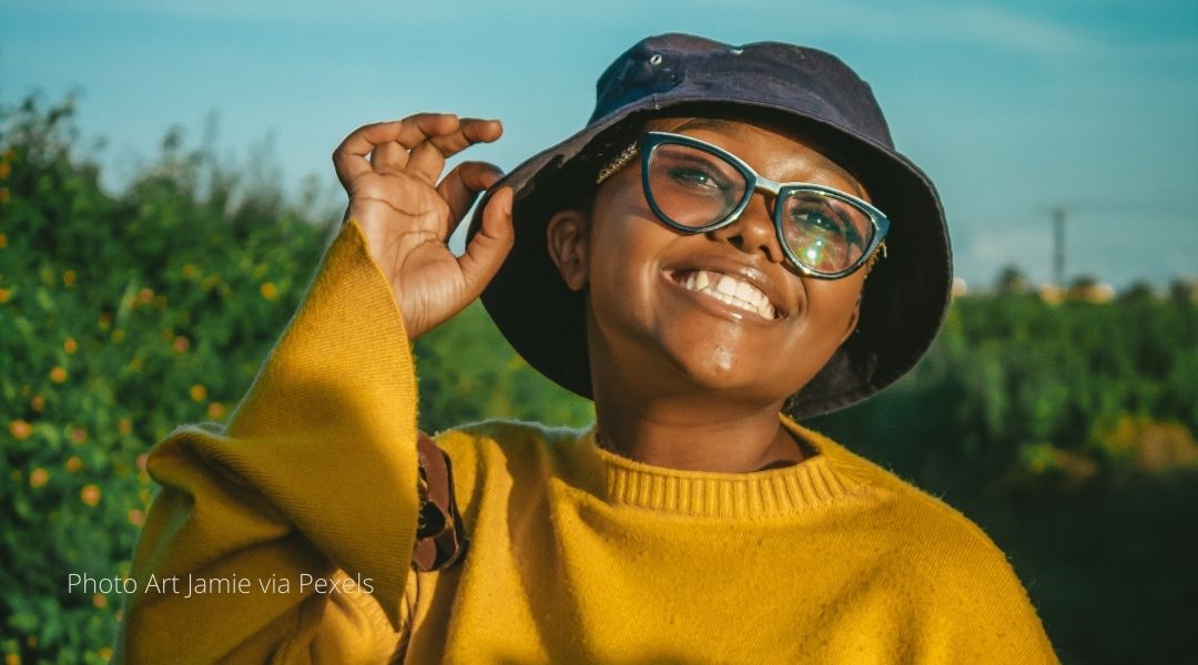 A young Kenyan woman tipping her hat and smiling 