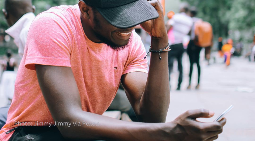 A young man smiling at his smart phone